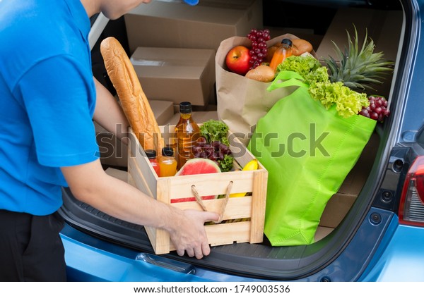 Food\
Delivery man giving fruit and vegetable shopping supermarket to\
receiver customer front house from truck car, express grocery\
service when coronavirus new normal lifestyle\
