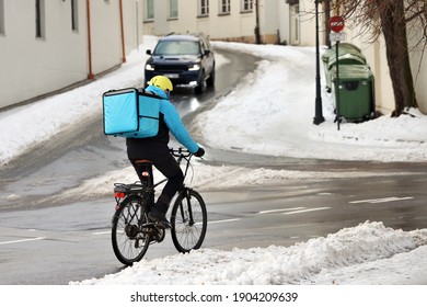 Food Delivery Man On Bicycle Working At Winter On Dirty City Street