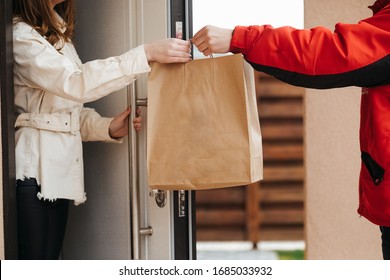 The food delivery man passes the craft package to the customer at the door of her house