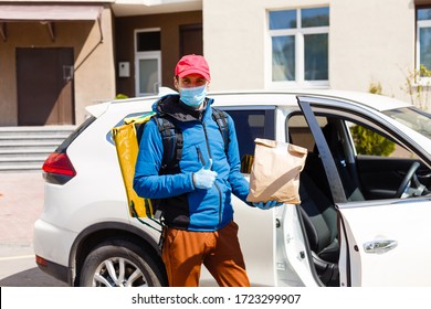 Food Delivery Man In A Protective Mask And Gloves With A Thermo Backpack Near A Car During The Quarantine Period