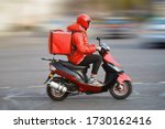 Food delivery moto scooter driver with red backpack behind back is on his way to deliver food. Courier on scooter delivering food. Quick shipping of goods to customers