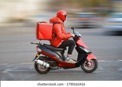 Food delivery moto scooter driver with red backpack behind back is on his way to deliver food. Courier on scooter delivering food. Quick shipping of goods to customers - Shutterstock ID 1730162416