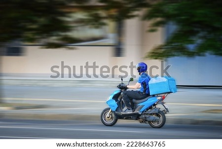 Food delivery moto scooter driver is on his way to deliver food. Courier on motor scooter delivering food. Delivery man in helmet, face mask, gloves ride scooter. Express food delivery, shop online