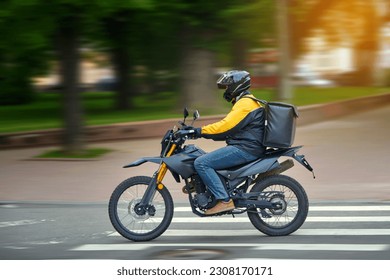 Food delivery motor bike driver with backpack behind back is on his way to deliver food. Courier on motorcycle delivering food. MOTION BLUR. Shipping of goods to customers from restaurant. Takeaway