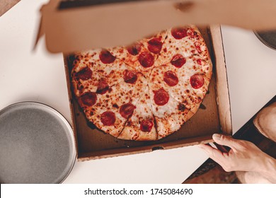 Food delivery. Ordering dinner online from the restaurant. New York style pizza and movie night. Family meal at home. Pepperoni and cheese topping. Cardboard box. Friday party. Comfort food.