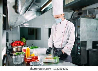 Food delivery in the restaurant. The chef prepares food in the restaurant and packs it in disposable dishes - Powered by Shutterstock