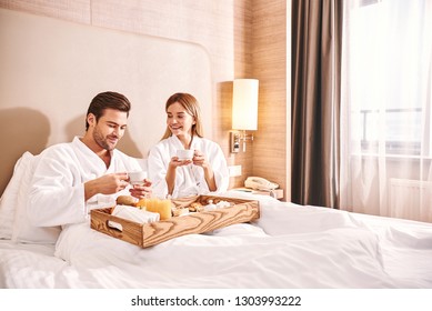 Food Delivery In The Room. Couple Are Eating In Hotel Room Bed