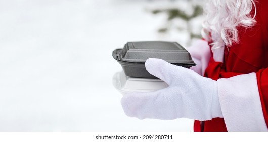 Food Delivery Service Containers In Hands Of Santa Claus Outdoor In Snow. Christmas Eve Promotion. Ready-made Hot Order, Disposable Plastic Box. New Year Holidays Catering. Copy Space, Mock Up