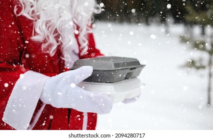 Food Delivery Service Containers In Hands Of Santa Claus Outdoor In Snow. Christmas Eve Promotion. Ready-made Hot Order, Disposable Plastic Box. New Year Holidays Catering. Copy Space, Mock Up