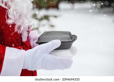 Food Delivery Service Containers In Hands Of Santa Claus Outdoor In Snow. Christmas Eve Promotion. Ready-made Hot Order, Disposable Plastic Box. New Year Holidays Catering. Copy Space, Mock Up