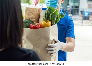 food delivery service man in blue uniform wearing protection face mask holding fresh food set bag to customer at door home, express delivery, quarantine, virus outbreak, takeaway food delivery concept - Shutterstock ID 1761800711