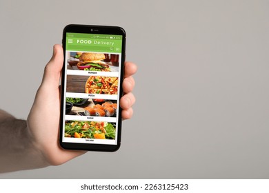 Food delivery service. Man choosing dish from menu on site using smartphone on light grey background, closeup and space for text - Shutterstock ID 2263125423
