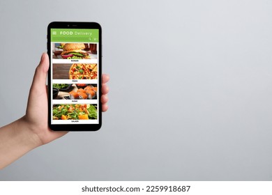 Food delivery service. Woman choosing dish from menu on site using smartphone on light grey background, closeup and space for text - Shutterstock ID 2259918687
