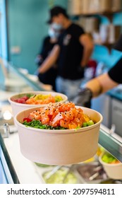 Food delivery of traditional Hawaiian cuisine. Packaging cooked poke bowls into paper bag, wearing protective gloves. Healthy vegetarian eating. Asian vegan raw meal.
