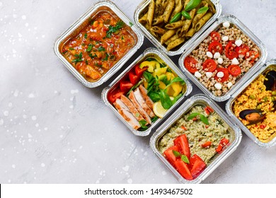 Food delivery.Different aluminium lunch box with healthy natural food pasta pesto, spelt, paella, quinoa, chicken salad, curry.  airlines food. airline meals and snacks . takeaway 
