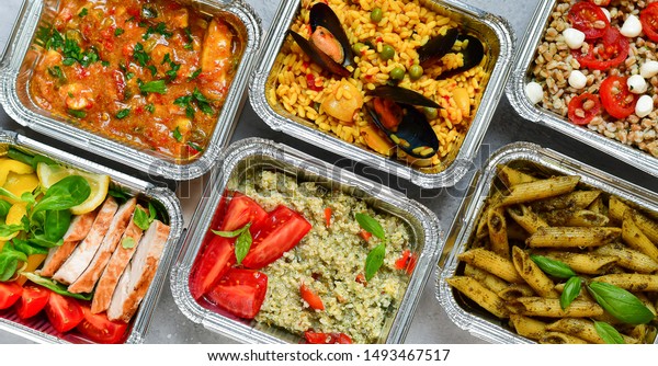 Food\
delivery.Different aluminium lunch box with healthy natural food\
pasta pesto, spelt, paella, quinoa, chicken salad, curry.  airlines\
food. airline meals and snacks . takeaway\
