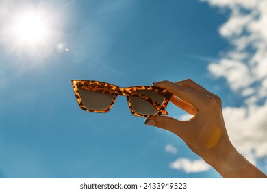 food, dessert and eating concept - close up of hand holding sunglasses over blue sky and cloud - Powered by Shutterstock