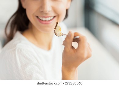 Food, Dessert, People And Lifestyle Concept - Close Up Of Smiling Young Woman Holding Fork And Eating Cake At Cafe Or Home