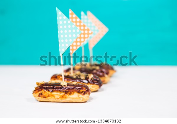 Food, desserts\
and bakery concept - traditional french eclairs with decorative\
flags on blue-white\
background