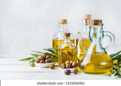 Food diet and nutrition concept. Assortment of fresh organic extra virgin olive oil in bottles with green leaves on a rustic wooden table. Copy space white background - Powered by Shutterstock