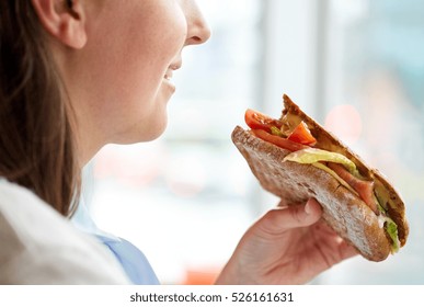 food, dinner and people concept - close up of happy smiling woman eating panini sandwich