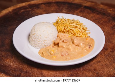 Food dish with chicken stroganoff and rice and chips
