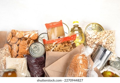 Food donations with pasta, rice, oil, peanut butter, canned food, jam and other  on light background, top view with copy space. Food donations or delivery concept. - Powered by Shutterstock