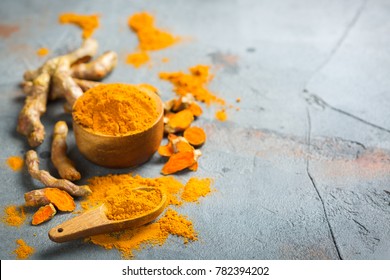 Food and drink, diet nutrition, health care concept. Raw organic orange turmeric root and powder, curcuma longa on a grunge cooking table. Indian oriental low cholesterol spices. Copy space background