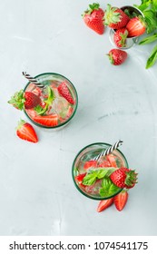 Food And Drink, Holidays Party Concept. Cold Fresh Alcohol Beverage Mojito Cocktail In Glasses With White Rum, Soda, Red Strawberry And Basil For Refreshment In Summer Days. Top View Background