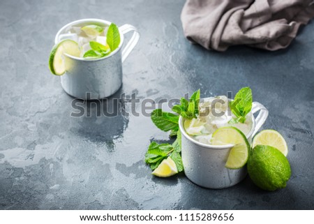 Food and drink, holidays party concept. Cold fresh classic beverage moscow mule cocktail in a silver mug with vodka, ginger beer. lime and mint for refreshment in summer days