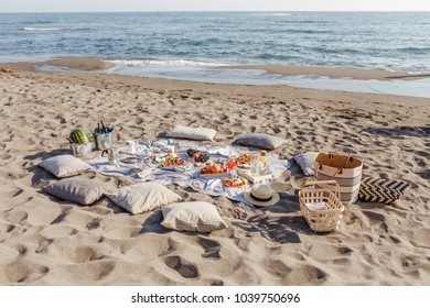 Food and drink for picnic set on sandy beach.