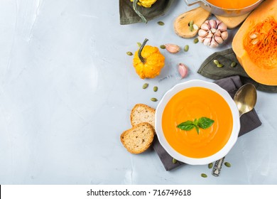 Food and drink, still life, diet and nutrition concept. Seasonal fall autumn roasted orange pumpkin carrot soup with ingredients on a table. Copy space cozy background, top view flat lay