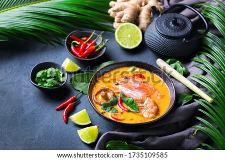 Food and drink, traditional Thai cuisine. Spicy tom yam kung, tom yum sour soup with shrimp, prawn, coconut milk, lemongrass and chili pepper in a bowl on a table