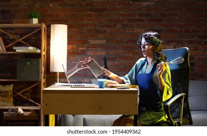 Food, Drinks, Cuisine. Young Caucasian Woman During Online Cooking Lesson Through Laptop At Home. Virtual Reality. Concept Of Remote Safe Entertaiments, Meetings During Quarantine. Copy Space For Ad.