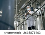A food factory researcher inspecting canned food conveyor belt machine. Worker checking on quality control of production line at food industry