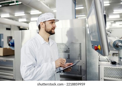 A Food Factory Supervisor Holds A Tablet In His Hands And Assesses The Productivity Of A Meat Cutting Machine.