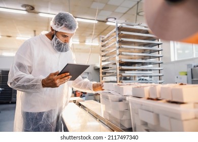 A food factory supervisor using tablet and assesses quality of food. - Shutterstock ID 2117497340