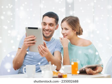 Food, Family, People And Technology Concept - Smiling Couple With Tablet Pc Computers Reading News And Having Breakfast At Home