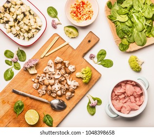 Food Flat Lay With Spinach, Chicken Meat , Chopped Champignon And Eggplant, Lemon And Vegetables On Cutting Board With Cooking Spoon On White Background, Top View 