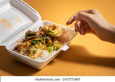 food in foam box .environmental pollution concept, dangerous to health,Hand holding spoon, eating food in foam box.