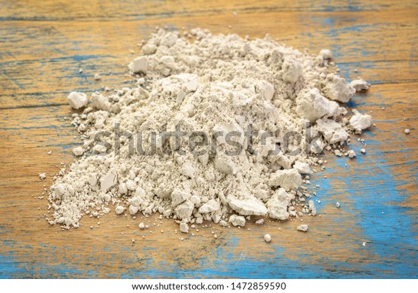 food grade diatomaceous earth supplement -\
small pile of powder on a grunge\
wood