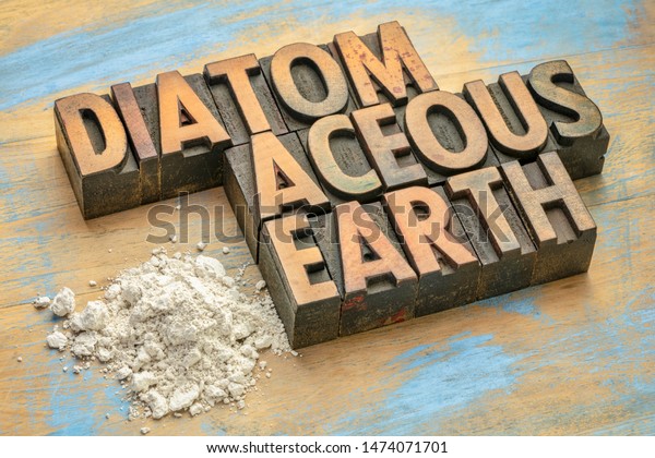 food grade diatomaceous earth supplement - small\
pile of powder on a grunge wood with a text in vintage letterpress\
wood type