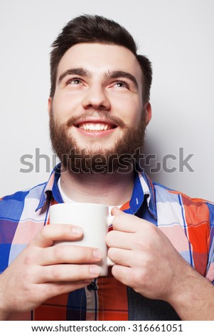 food, happiness and people concept: young bearded man with a cup of coffee against grey background