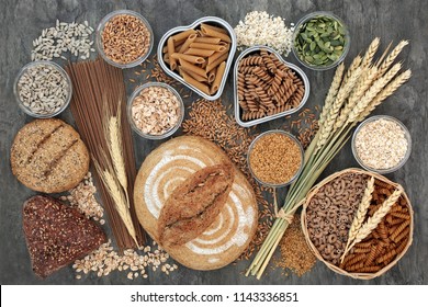 Food high in dietary fibre with whole grain bread and seeded rolls, whole wheat pasta, seeds, cereals and grains on marble background top view. Foods high in antioxidants, omega 3 and vitamins.  - Powered by Shutterstock