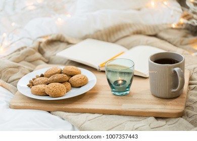 Food, Hygge And Comfort Concept - Oatmeal Cookies, Tea, Diary And Candle In Holder At Home