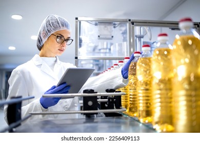 Food inspector or technologist taking good care of bottled vegetable oil inside bottling plant. - Powered by Shutterstock