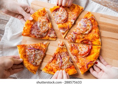 Food, Italian Kitchen And Eating Concept - Close Up Of Hands Taking And Sharing Homemade Pizza On Wooden Table