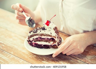 Food, Junk-food, Culinary, Baking And Holidays Concept - Close Up Of Woman Eating Chocolate Cherry Cake With Spoon And Sitting At Wooden Table