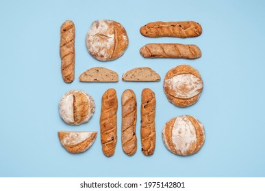 Food knolling with homemade sourdough bread. Round loaves and baguettes made with sourdough arranged symmetrically on a blue background.