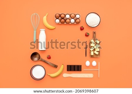 Food knolling on orange background with crepes ingredients and kitchen utensils. Making crepes flat lay, kitchen tools, and ingredients arranged with copy space in the middle.